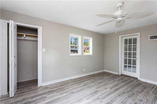 unfurnished bedroom featuring visible vents, ceiling fan, baseboards, wood finished floors, and a closet