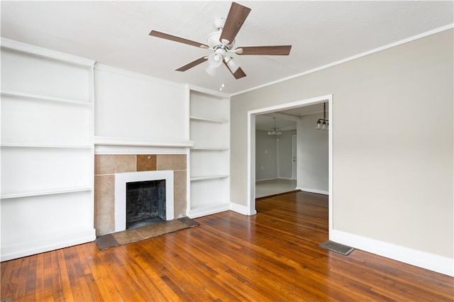 unfurnished living room featuring baseboards, a tiled fireplace, ornamental molding, a ceiling fan, and wood-type flooring