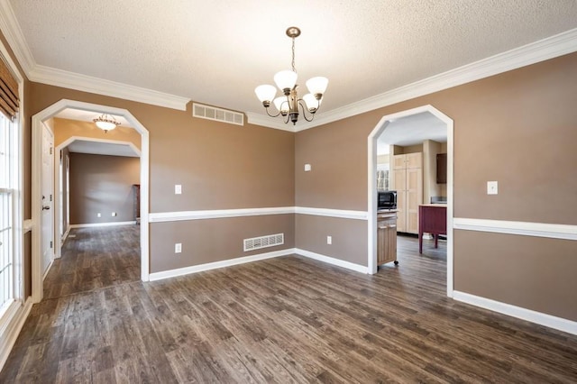 empty room with dark wood-type flooring, arched walkways, visible vents, and crown molding