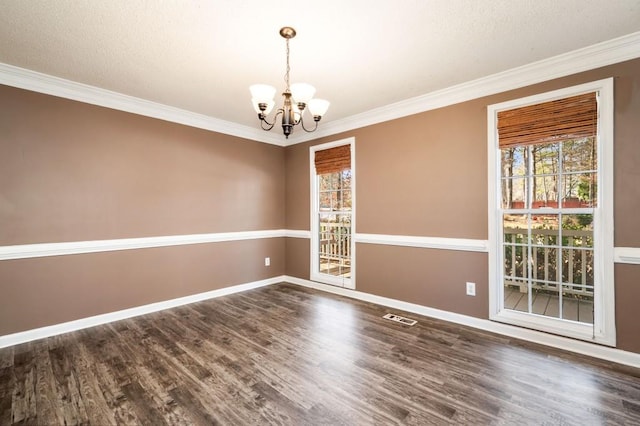 empty room featuring dark wood-style floors, crown molding, visible vents, a chandelier, and baseboards