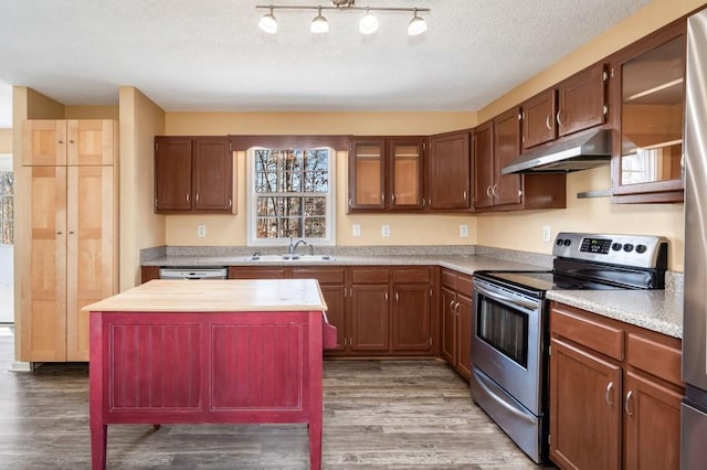 kitchen with appliances with stainless steel finishes, hardwood / wood-style floors, sink, a center island, and a textured ceiling