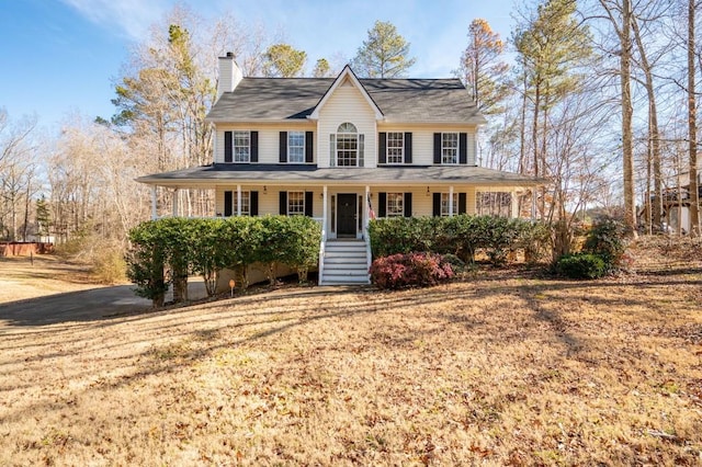 view of front of property with a porch, a chimney, and a front yard