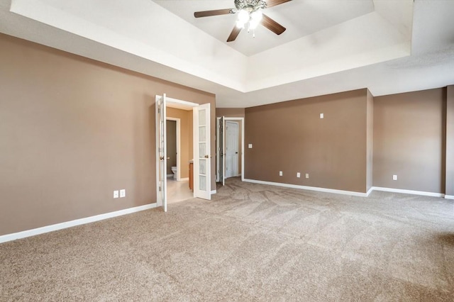 unfurnished bedroom with french doors, ceiling fan, a raised ceiling, and carpet floors