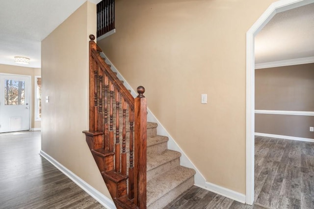 stairway with crown molding and wood-type flooring