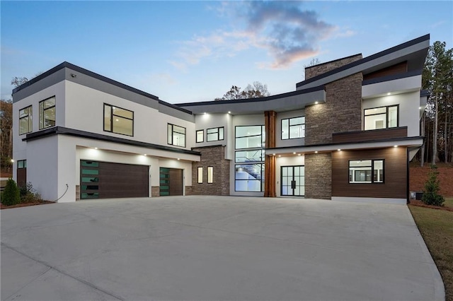 1678 Thomas Dr, Hoschton, GA 30548 - contemporary house with stone siding, driveway, an attached garage, and stucco siding