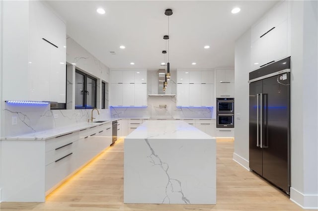 1678 Thomas Dr, Hoschton, GA 30548 - kitchen featuring modern cabinets, appliances with stainless steel finishes, wall chimney exhaust hood, a sink, and white cabinetry