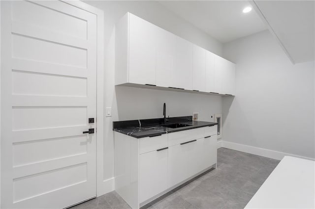 1678 Thomas Dr, Hoschton, GA 30548 - kitchen with a sink, white cabinetry, dark countertops, baseboards, and recessed lighting