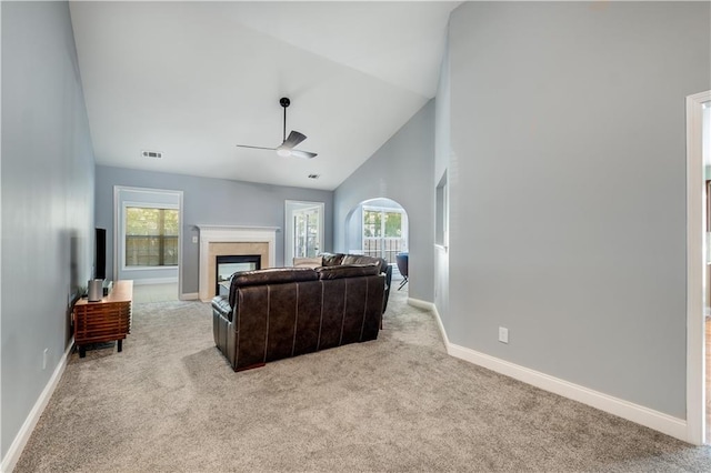 living room with a fireplace, ceiling fan, light carpet, and high vaulted ceiling