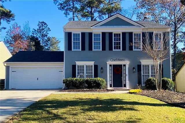 colonial inspired home featuring a garage and a front lawn