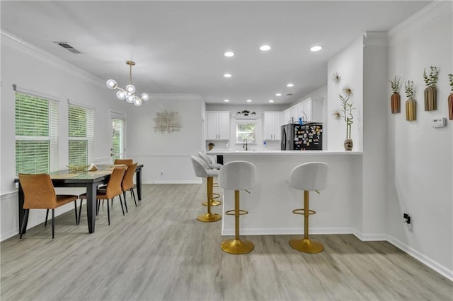 kitchen featuring freestanding refrigerator, crown molding, white cabinetry, plenty of natural light, and a sink