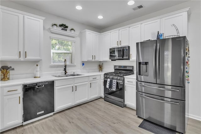 kitchen with stainless steel appliances, a sink, white cabinets, light countertops, and recessed lighting