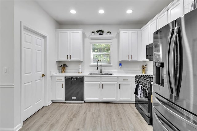 kitchen featuring black appliances, a sink, white cabinets, light countertops, and light wood-type flooring