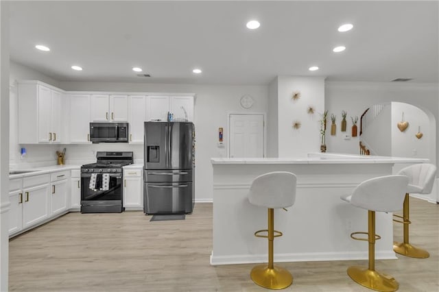 kitchen with stainless steel appliances, white cabinetry, a kitchen bar, recessed lighting, and ornamental molding