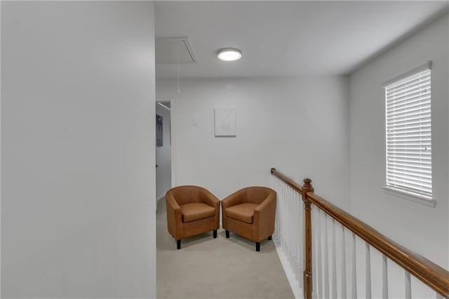 sitting room with attic access, carpet flooring, and an upstairs landing