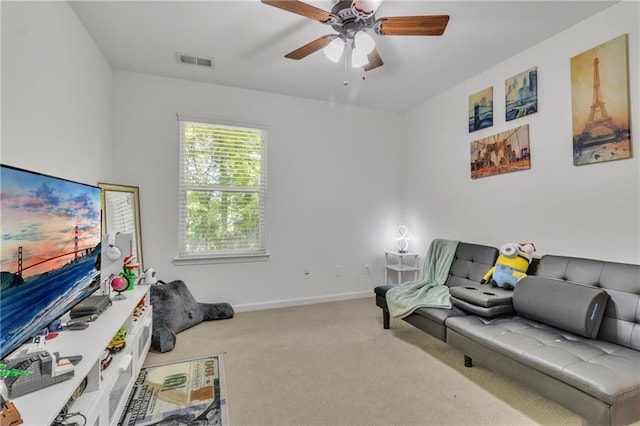carpeted living area with a ceiling fan and baseboards