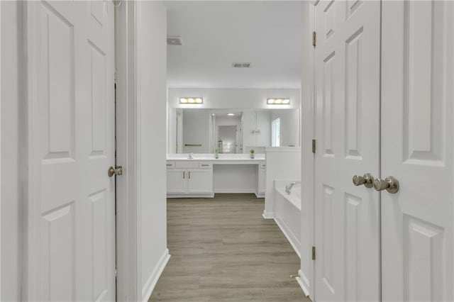 full bath with a garden tub, double vanity, baseboards, and wood finished floors
