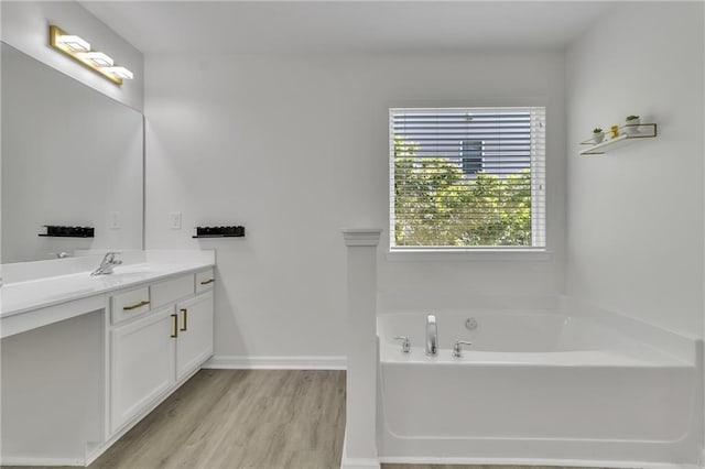 full bathroom featuring wood finished floors, vanity, a bath, and baseboards
