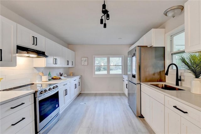 kitchen featuring a sink, appliances with stainless steel finishes, under cabinet range hood, white cabinetry, and decorative backsplash