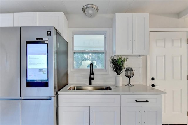 kitchen featuring a sink, refrigerator with glass door, and white cabinets