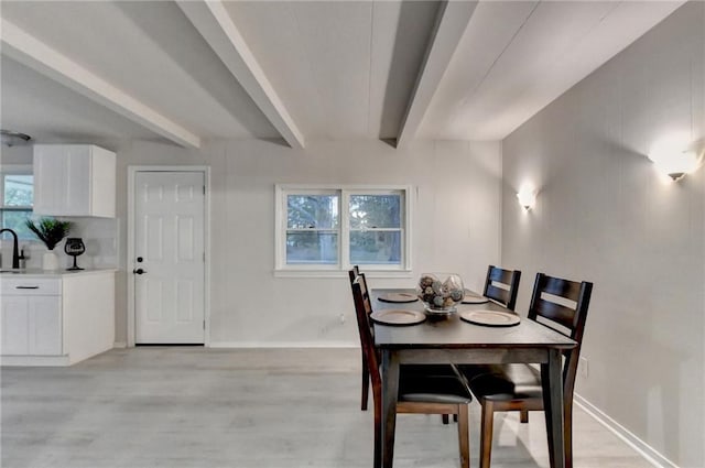 dining area with baseboards, light wood-type flooring, and beamed ceiling