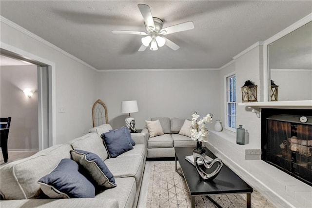 living room featuring a textured ceiling, ornamental molding, a fireplace, and a ceiling fan