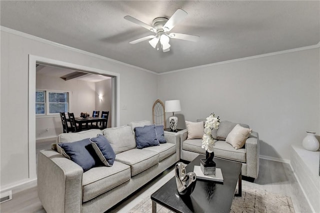 living area with light wood-style floors, baseboards, a ceiling fan, and crown molding