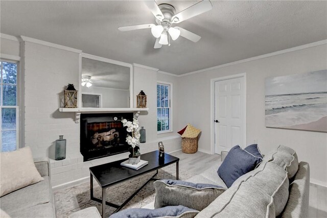 living area featuring crown molding, ceiling fan, a fireplace with raised hearth, and wood finished floors