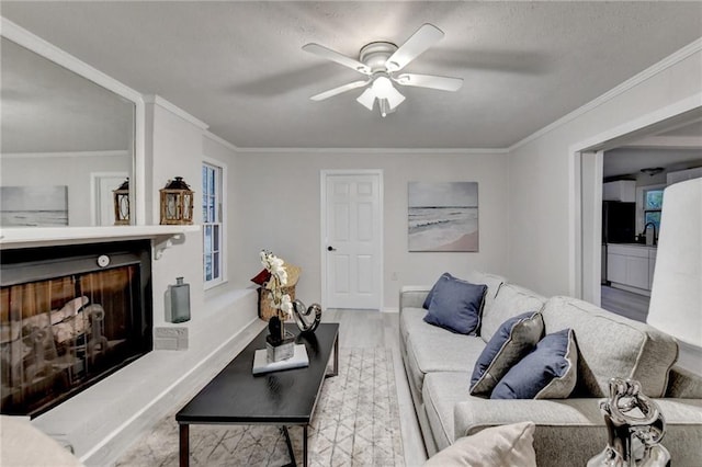living area featuring baseboards, a ceiling fan, ornamental molding, and wood finished floors