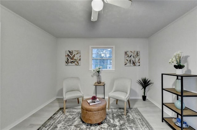living area featuring baseboards, a ceiling fan, and wood finished floors