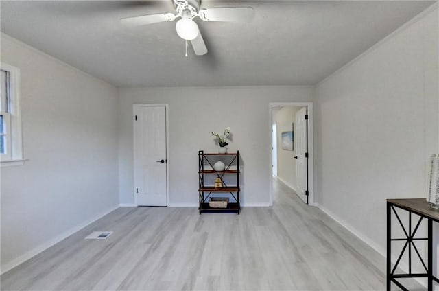 unfurnished room featuring light wood finished floors, baseboards, a ceiling fan, and visible vents