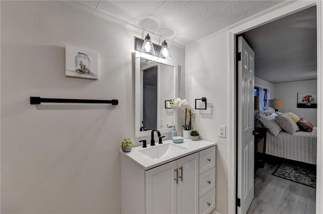 ensuite bathroom with ensuite bathroom, a textured ceiling, vanity, ornamental molding, and wood finished floors
