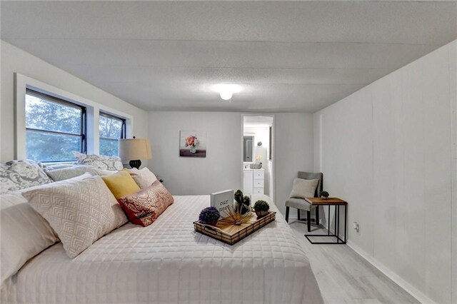 bedroom with light wood-style floors, baseboards, and ensuite bathroom