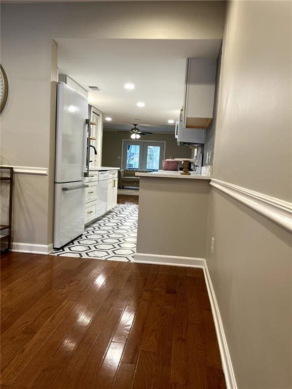 kitchen with kitchen peninsula, white appliances, white cabinetry, and light hardwood / wood-style flooring