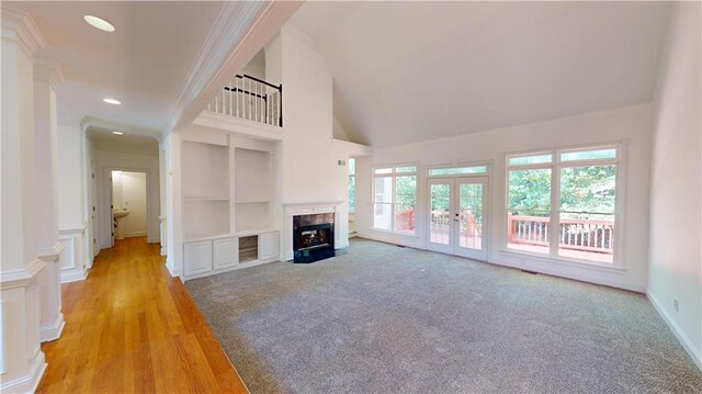 unfurnished living room with built in shelves, french doors, high vaulted ceiling, and light hardwood / wood-style floors