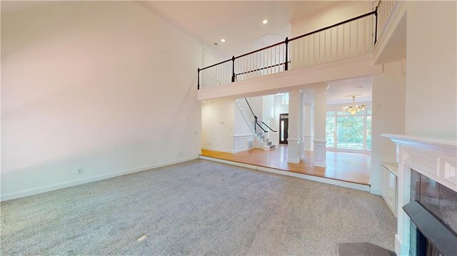 unfurnished living room with ornate columns, a towering ceiling, and hardwood / wood-style floors