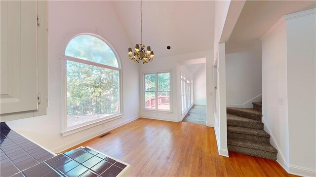 interior space with an inviting chandelier, high vaulted ceiling, and light wood-type flooring