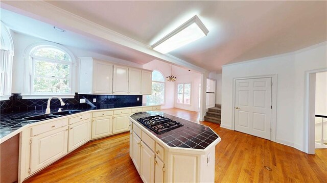 kitchen featuring a healthy amount of sunlight, a kitchen island, black gas stovetop, tile countertops, and light hardwood / wood-style floors