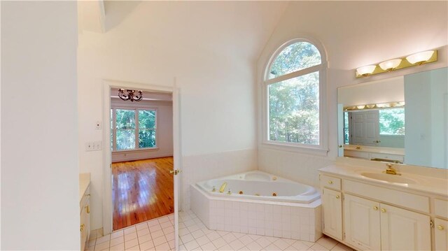 bathroom with vanity, hardwood / wood-style flooring, plenty of natural light, and tiled tub