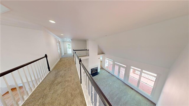 hall featuring vaulted ceiling and light colored carpet