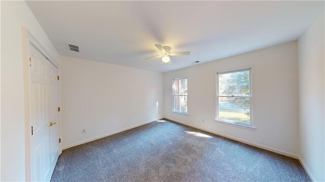 unfurnished room featuring ceiling fan and dark carpet