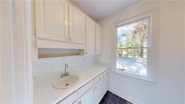 kitchen with white cabinets, sink, and dark tile patterned flooring