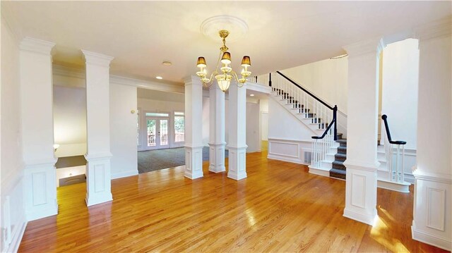 interior space featuring ornamental molding, french doors, a notable chandelier, and light hardwood / wood-style floors