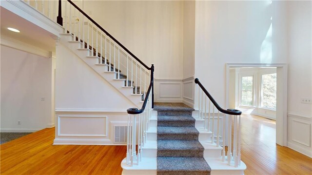 stairway featuring a towering ceiling and wood-type flooring