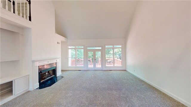 unfurnished living room featuring french doors, high vaulted ceiling, and carpet flooring