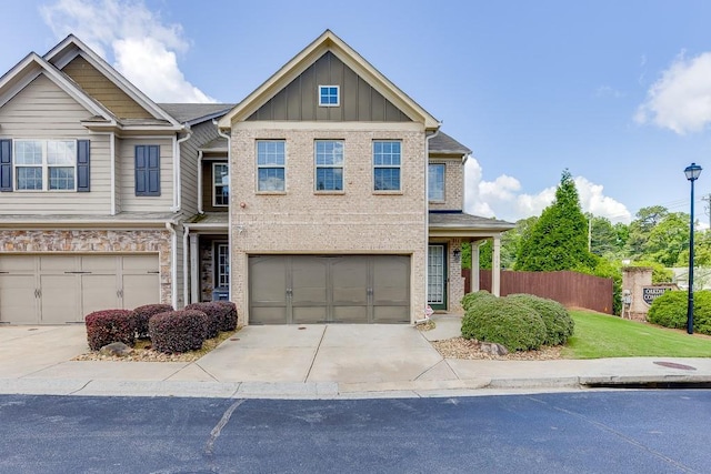 townhome / multi-family property with board and batten siding, driveway, an attached garage, and brick siding