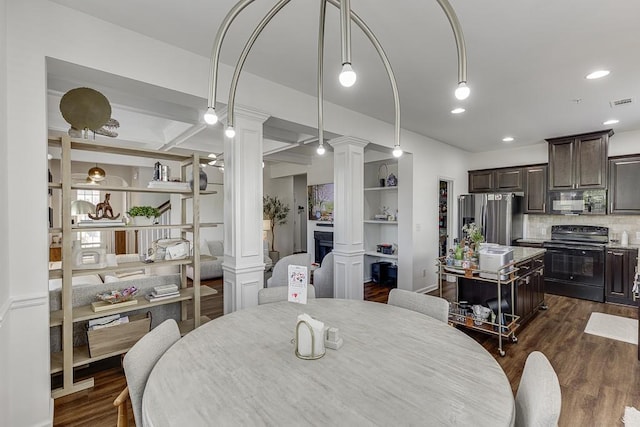 dining space featuring decorative columns, dark wood-style floors, recessed lighting, and a fireplace