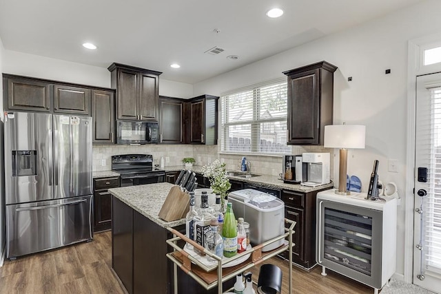 kitchen with black appliances, beverage cooler, dark brown cabinetry, wood finished floors, and decorative backsplash