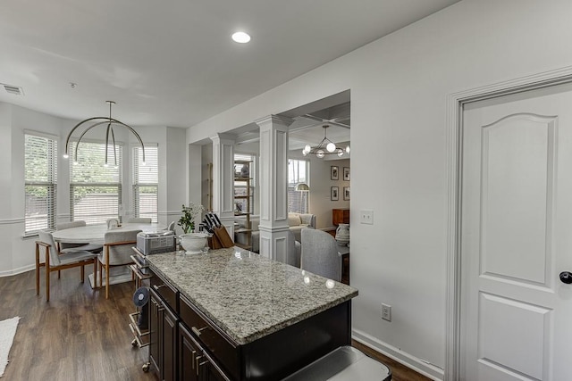 kitchen featuring ornate columns, dark wood-style flooring, light stone countertops, a chandelier, and recessed lighting