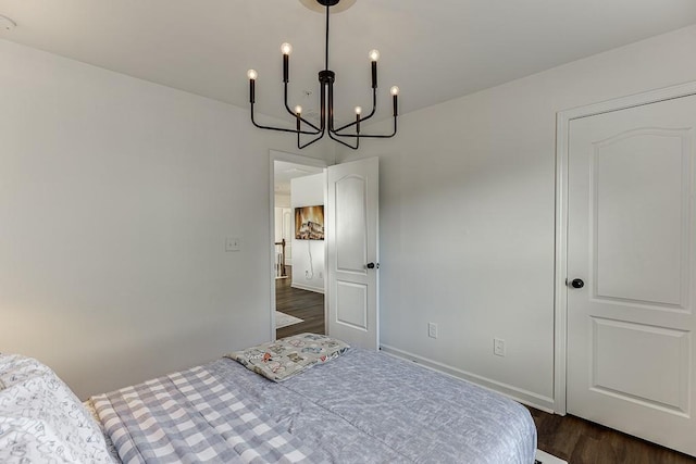 bedroom featuring a chandelier, dark wood finished floors, and baseboards