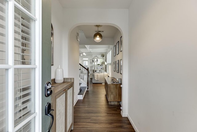 entrance foyer featuring arched walkways, dark wood-style floors, baseboards, and stairway